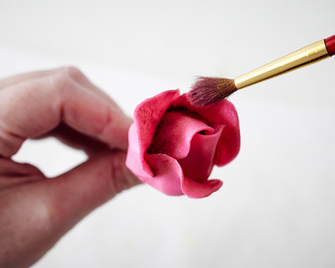 Coloque a rosa em um vidro para secar. Depois de seco, use um pincel para revestir as fendas da rosa com brilho e, em seguida, tire o excesso.